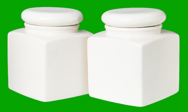 Two white ceramic jars for food storage in the kitchen isolate on a green background