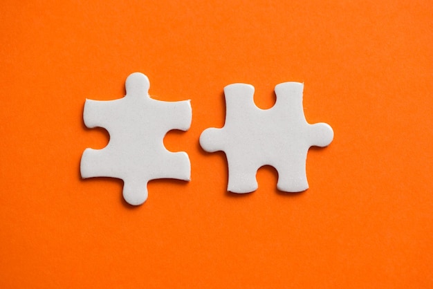 Two white details of puzzle on orange background