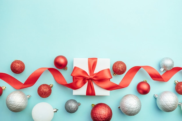 Two white gift boxes with red and silver ornaments on blue background. Christmas background. Flat lay, top view, copy space.