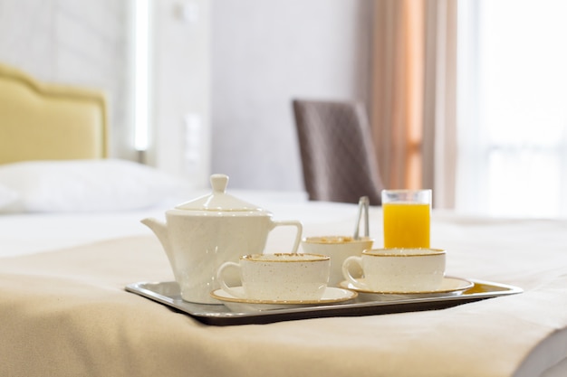 Two white mugs on a tray white bed, breakfast concept