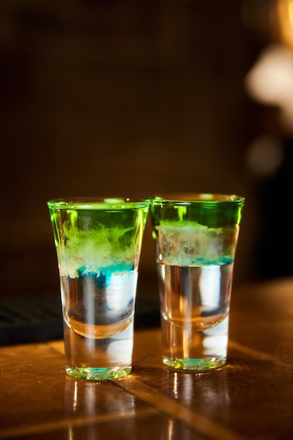 Two whitegreen alcoholic drinks shots on the bar counter