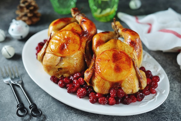 Two whole roasted chicken with cranberries and orange slices