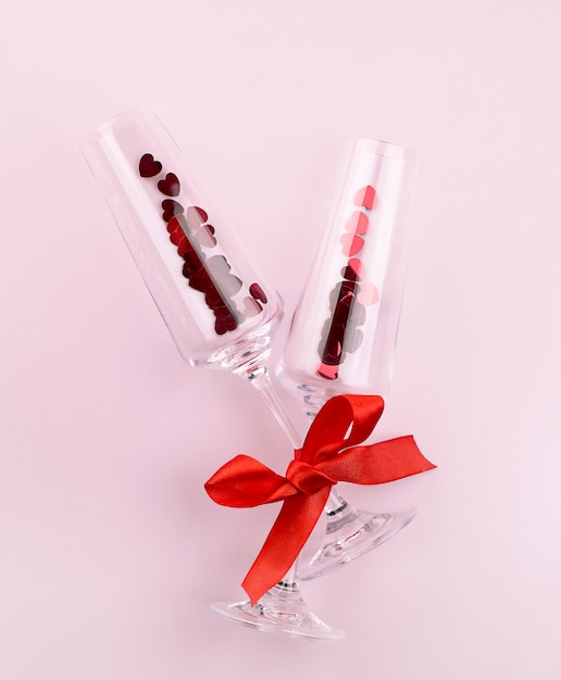 Two wineglasses with heart-shaped confetti with a tied ribbon. valentine's day concept