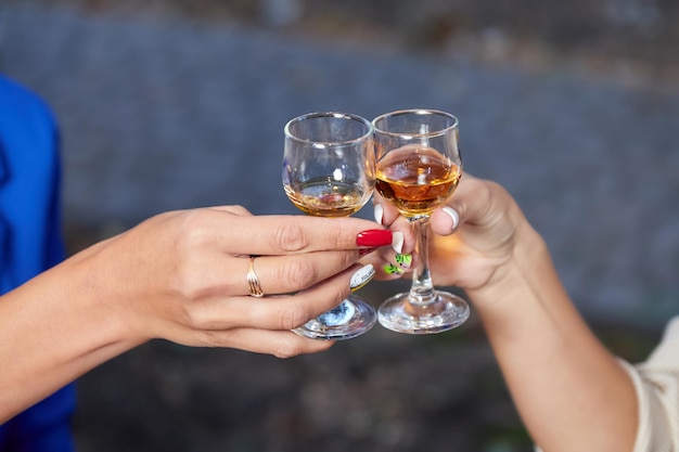 Two woman clink glasses with alcohol