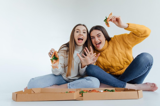 Two woman friends eating  pizza.