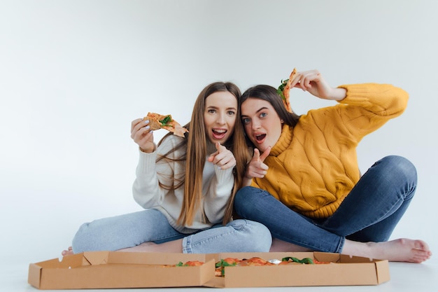 Two woman friends eating  pizza.