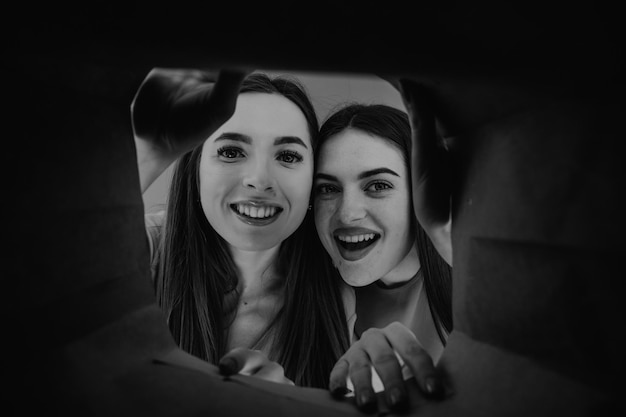 Two woman looking inside cardboard box