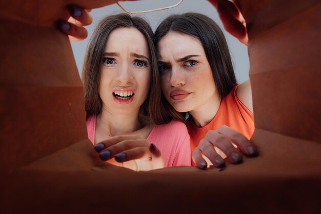 Two woman looking inside cardboard box