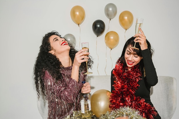 two women are having a party with balloons and a bottle of champagne