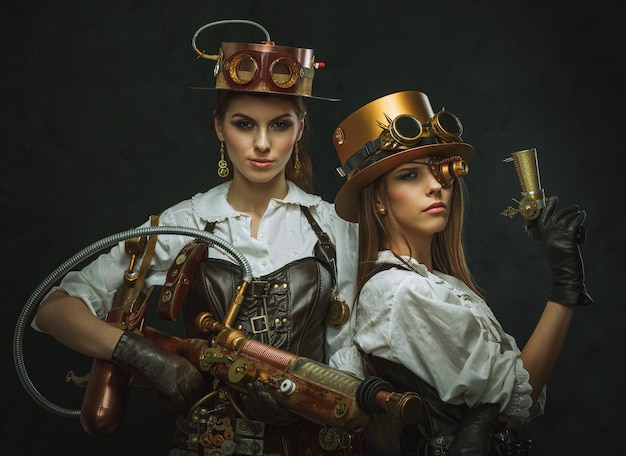 Two women dressed in the style of steampunk with arms