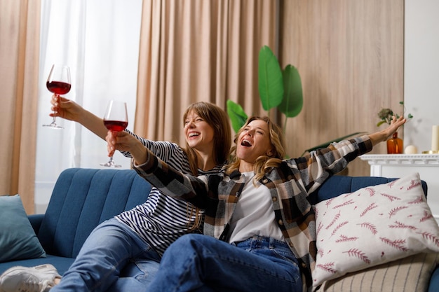 Two women friends of different ages have fun drinking wine during home party