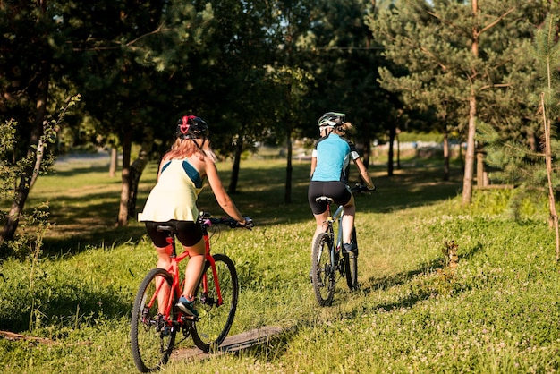 Two women friends riding bikes offroad at the forest