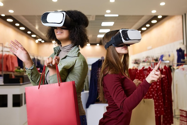 Two women in modern virtual reality headsets having expirience in shopping at lingerie store