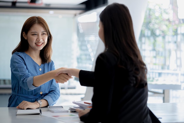 Two women shake hands two businesswomen shake hands as they meet to discuss brainstorming and marketing plans to find more profitable ways to grow Business management ideas for profitable growth