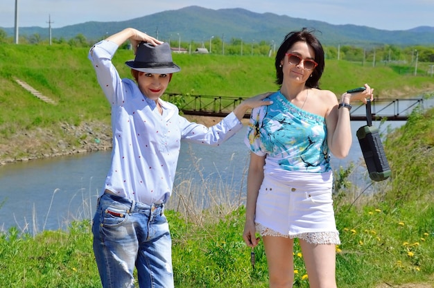 Two women sisters have fun outdoor nearby a river