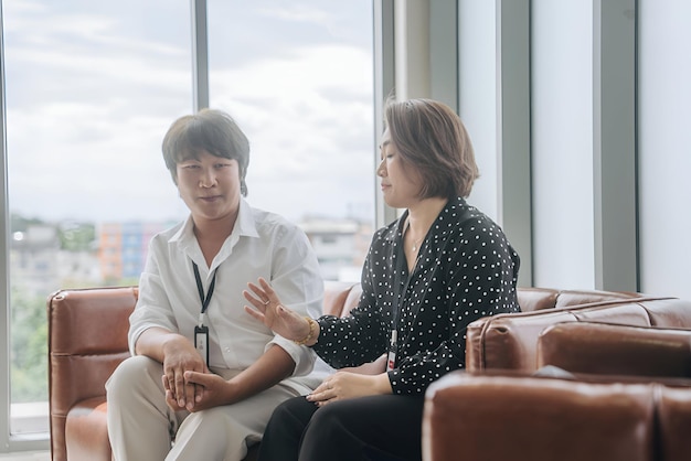 two women sit in a room one has a white shirt that says  the word  on it