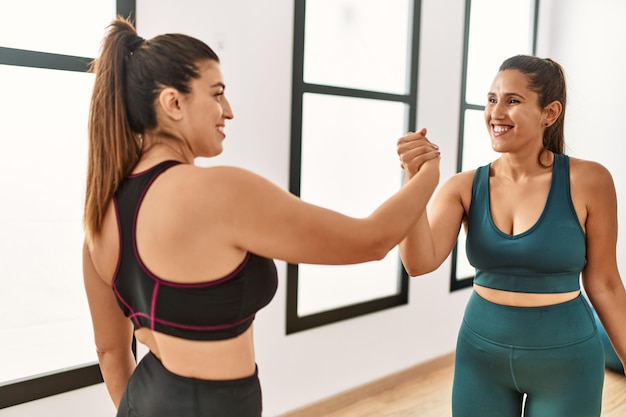 Two women smiling confident shake hands standing at sport center