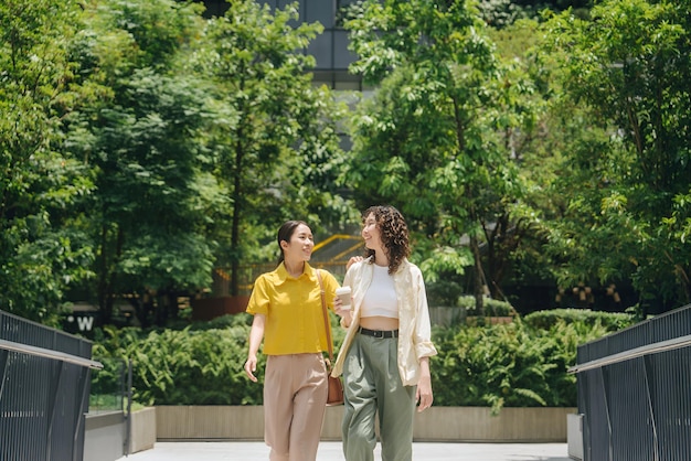 two women walking in a park one wearing a yellow shirt and the other has a white shirt on