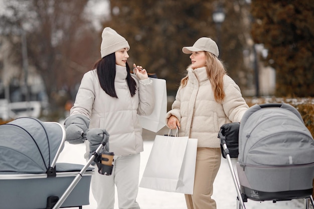 Two women with baby strollers walking in the city together and talking