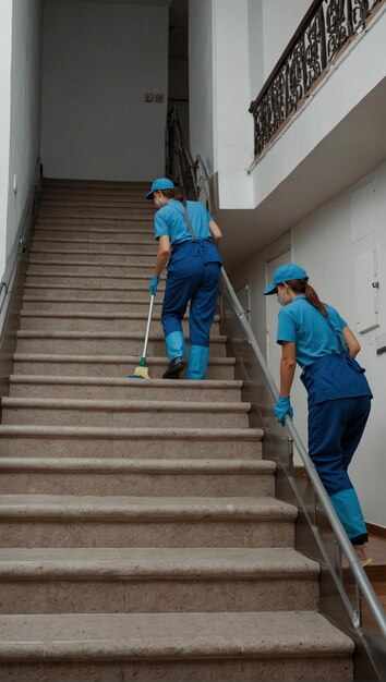 two women with brooms are going up the stairs