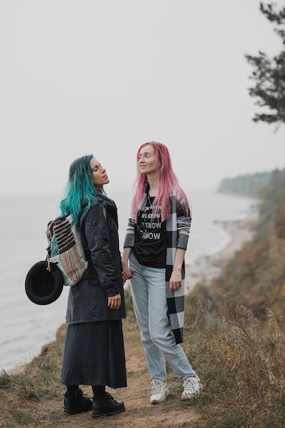 two women with pink and blue hair are holding hands and smiling