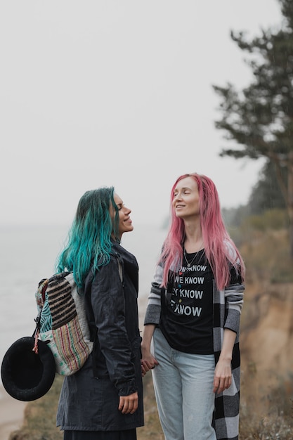 two women with pink and blue hair are holding hands and smiling