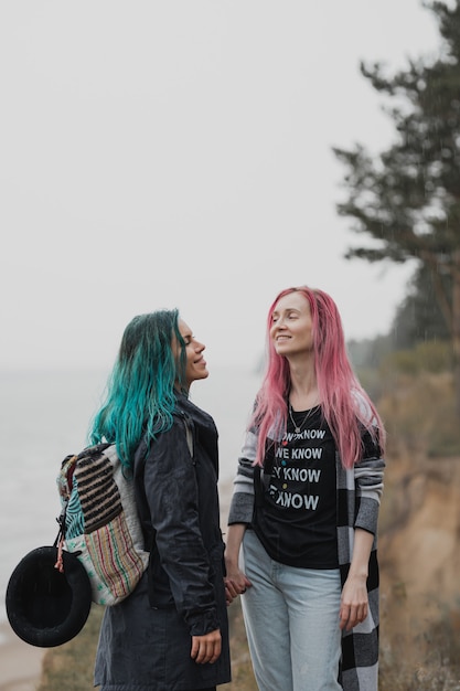 two women with pink and blue hair are holding hands and smiling