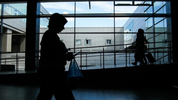 Two womens silhouette walking by the panoramic window background