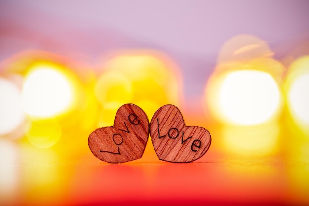 Photo two wood hearts on red background with blured lights. love concept for valentines day.