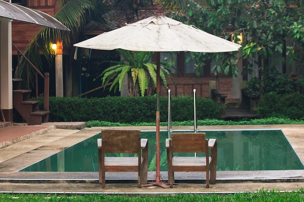 Two wooden chairs are located beside the pool