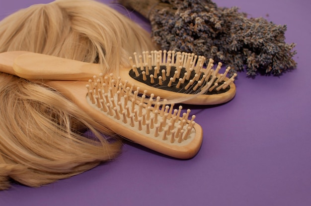 Two wooden combs blonde hair and a bouquet of lavender on a purple background