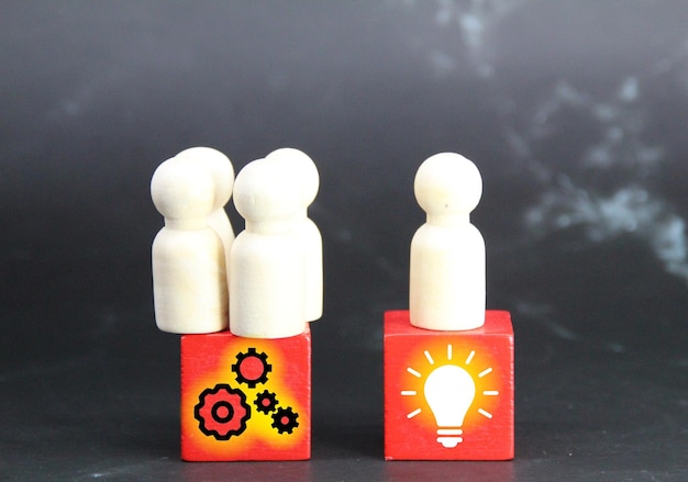 Two wooden figures are next to each other with a light bulb and a symbol that says leader management