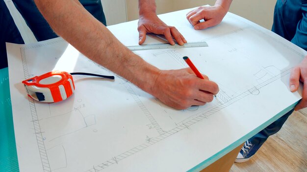 Photo two workers are developing a scheme of the house the project is drawn on paper