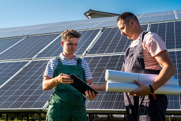 Two workers in a uniform talk about installation solar panel Alternative energy