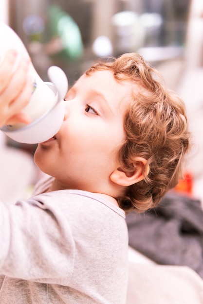 Two year old boy drinking a bottle at home at night before going to bed