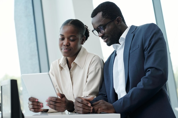 Two young african american colleagues in formalwear looking through data