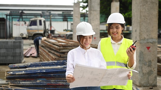 Two young architects wearing safety helmet and vest inspecting industrial building construction site Industry Engineer construction concept