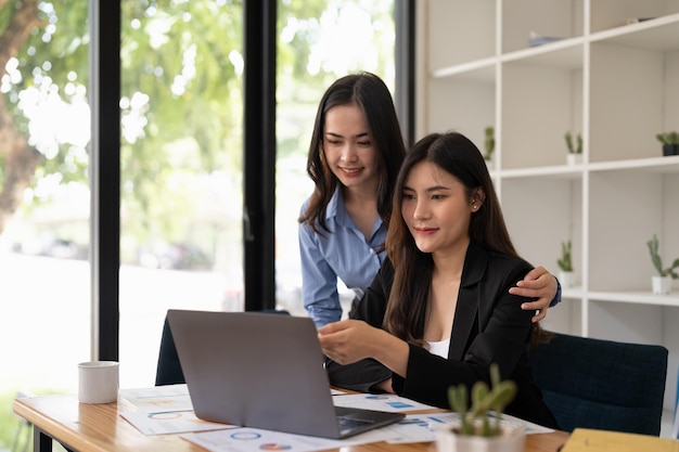 Two young asian woman working on laptop computer at office