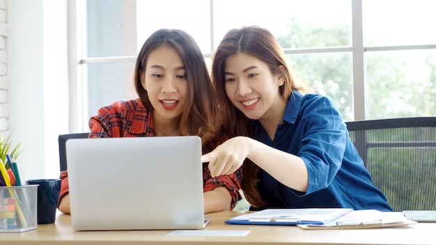  Two young asian women working with laptop computer at home office with happy emotion moment