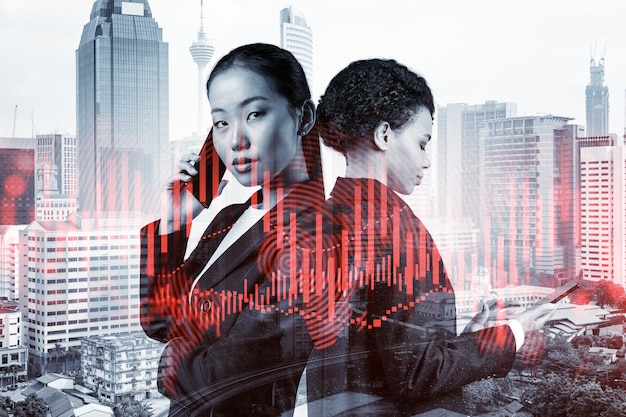 Two young astonishing businesswoman in suits working on forecasting trading corporate strategy at fund Forex chart Kuala Lumpur on background Double exposure