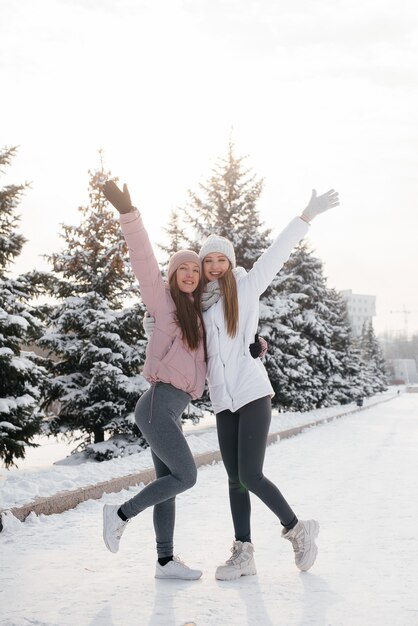 Two young athletic girls walking and playing sports on a sunny winter day. A healthy way of life.