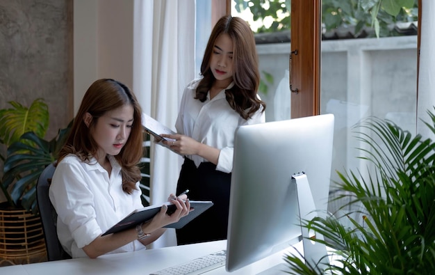 Two young beautiful asian business woman in the conversation exchanging ideas at work