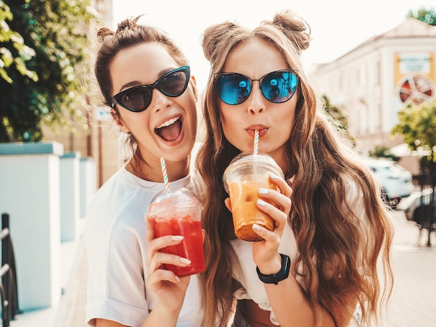 Two young beautiful smiling hipster female in trendy summer clothes