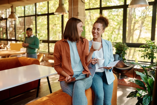 Two young business woman enjoying pleasant conversation in coworking space