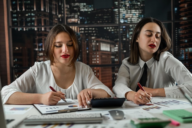 Two young business women analyzing financial documents at office Concept of economic growth strategy Teamwork