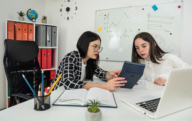 Two young business women talking and filling 1040 tax form