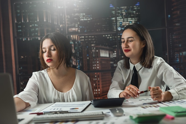 Two young business women working together and discussing about financial document graph and diagram