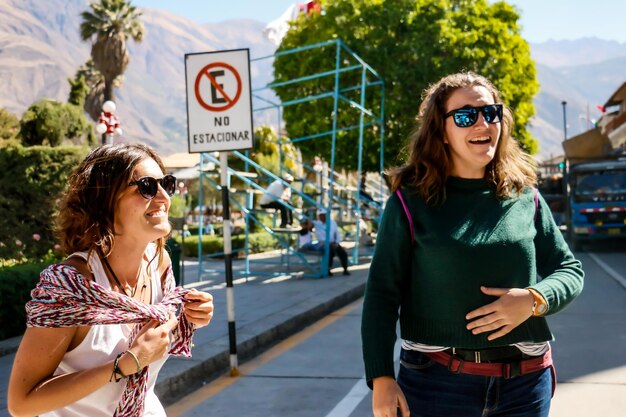 Two young Caucasian female friends chatting on a sunny street