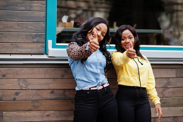 Photo two young college african american woman friends show thumb up.