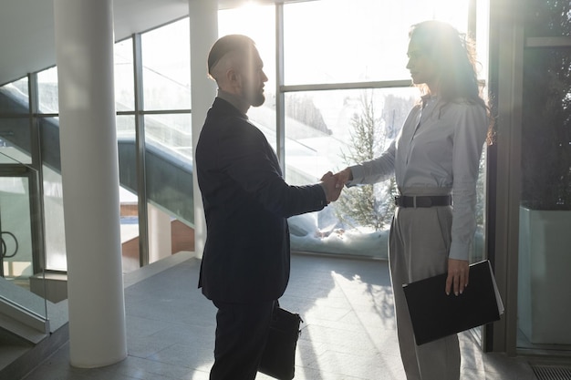 Two young confident business partners in formalwear shaking hands